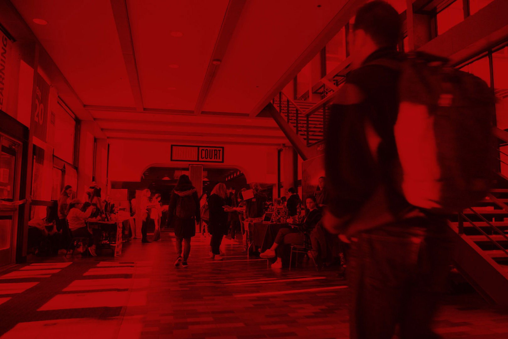 Still from "Students on the Issues That Matter Most to Them in the 2020 Presidential Election" video; photo of students walking in the hallway leading to Union Court with red overlay.