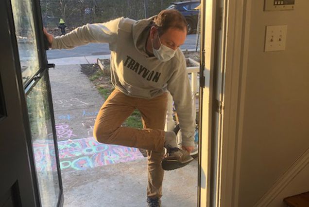 A photo of Joshua Barocas removing his shoes before entering his home after treating COVID-19 patients.