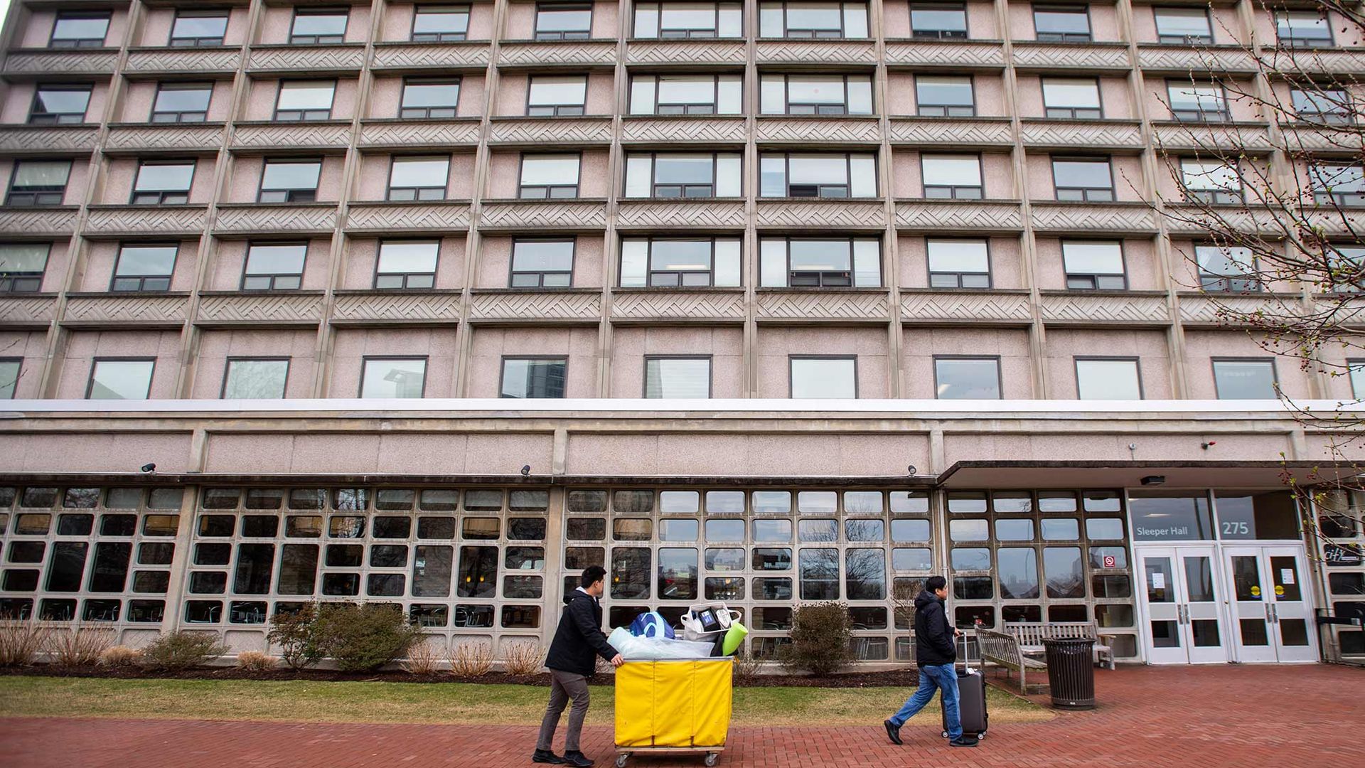 Students on West Campus push a yellow cart and wheel a suitcase on March 20,200 during the forced move out brought on by the threat of COVID-19. 