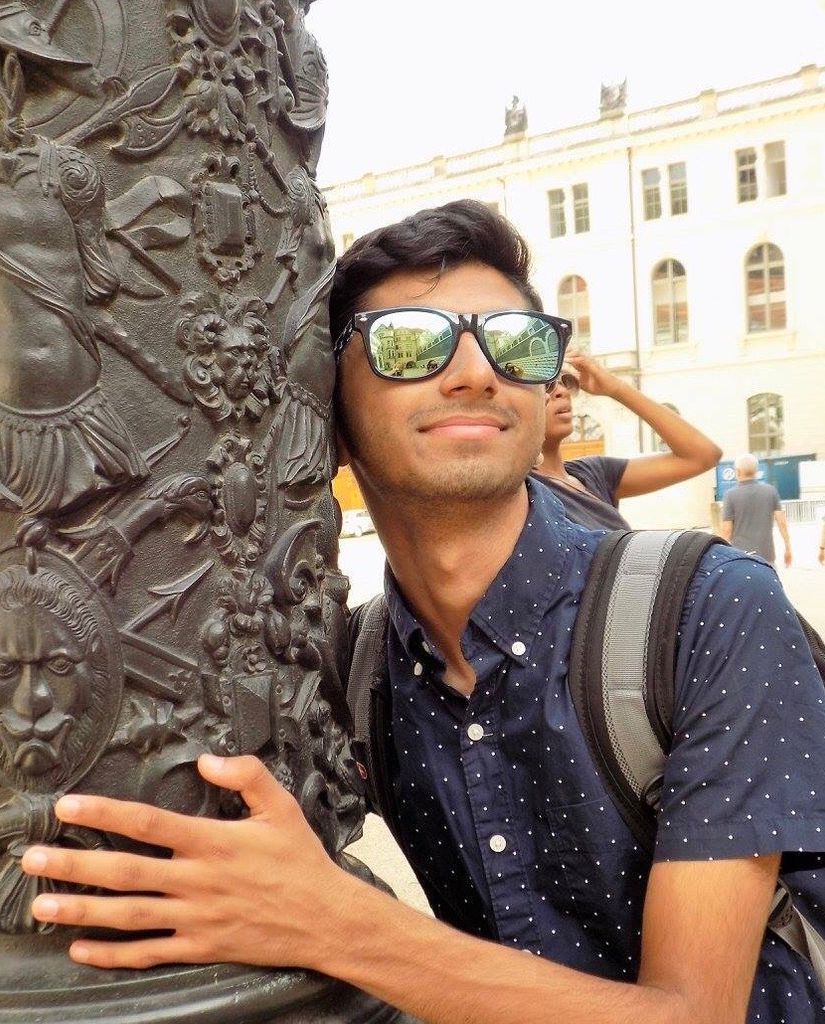 Photo of Kush Mehta (CAS’20) in reflective sunglasses holding a metal column with a greco-roman design on it.