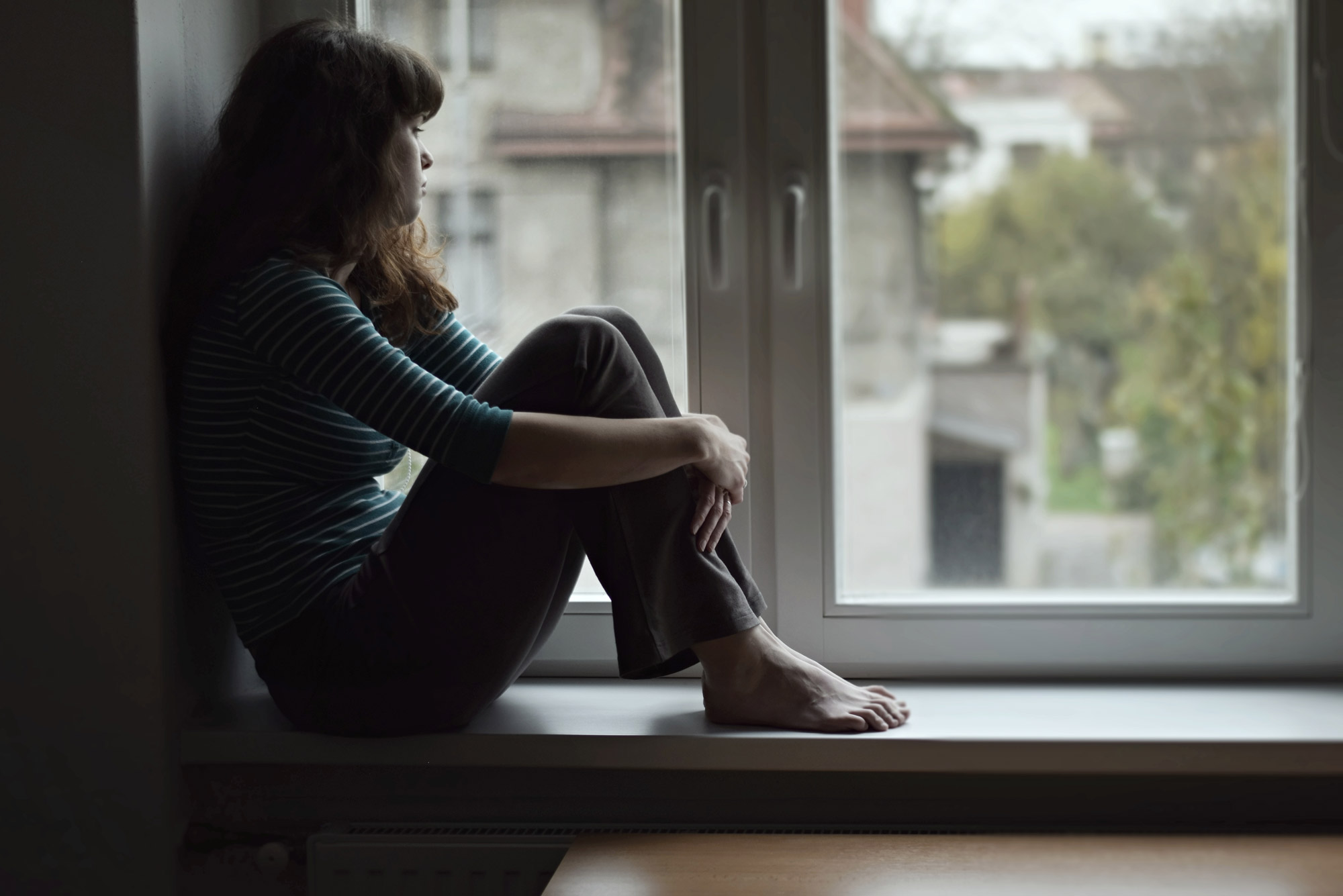 A photo of a woman staring out of a window