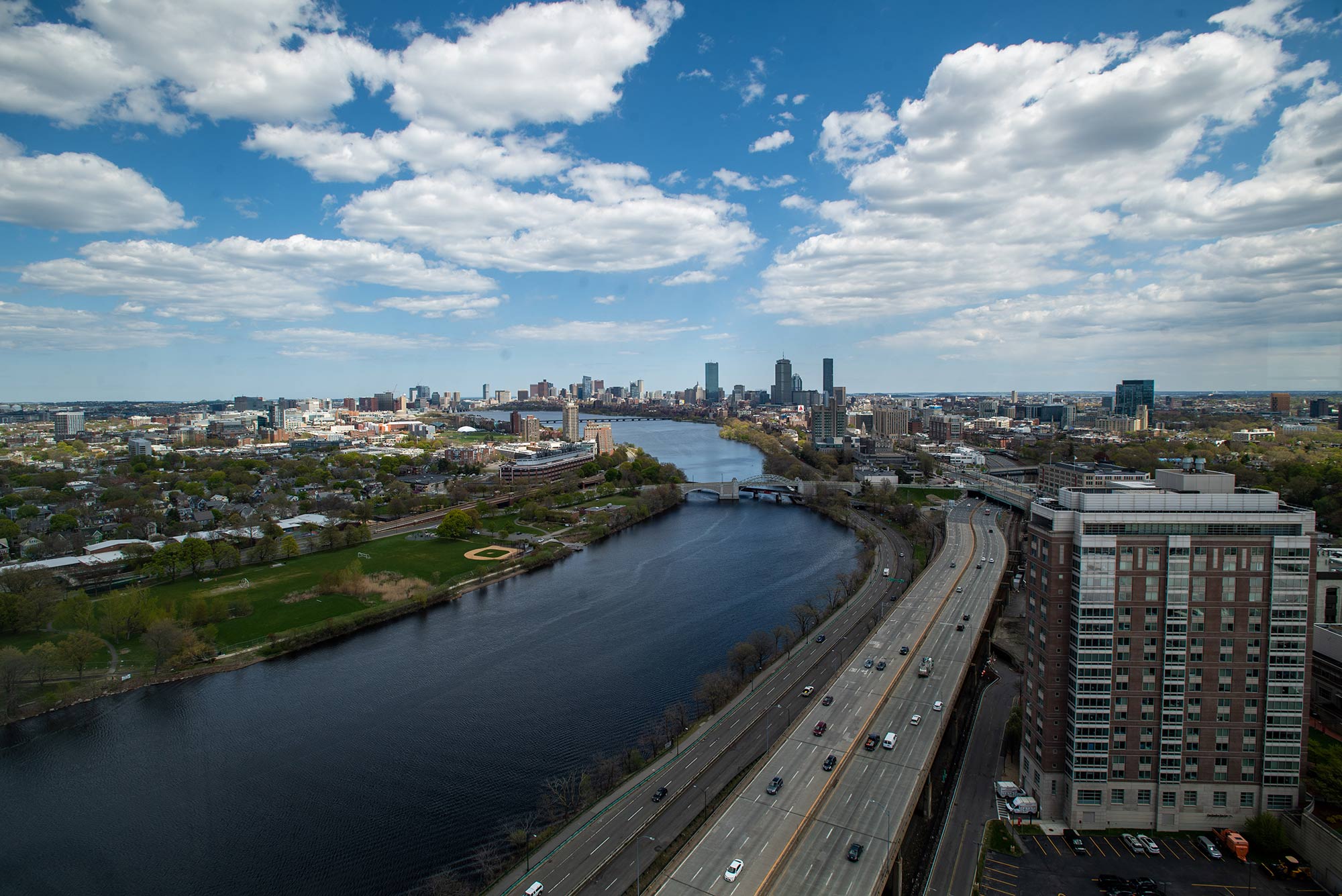 Photo of the Charles River from the 26th floor of Student Village 2 May 7. Blue skies with puffy clouds are seen, as well as Storrow Drive and the Boston skyline.