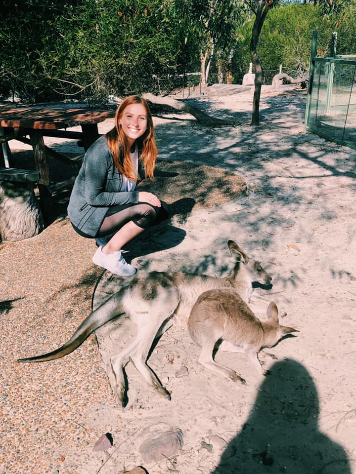 Photo of Nicole McPherson (COM’20) kneeling next to wallabies. 