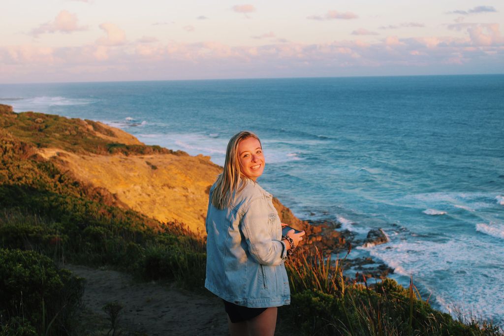 Photo of Maryann Lennon (CAS’20) with a rocky ocean shore at sunset in the background.