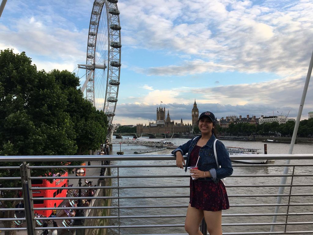 Photo of Catherine Monroy (CGS’18, Pardee’20) holding a drink with the London Eye and London skyline in the background.