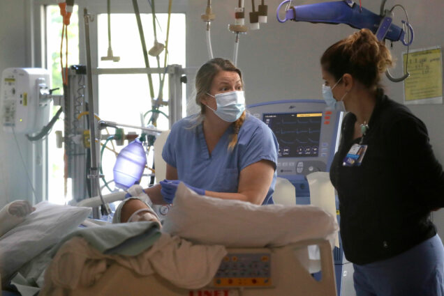 In this May 8, 2020, file photo, registered nurse Katie Hammond, left, works with another nurse on a patient in the COVID-19 Intensive Care Unit at Harborview Medical Center , in Seattle. The number of deaths in Washington because of the coronavirus has reached 1,000, the Washington State Department of Health reported Saturday, May 16, 2020. The agency added eight more deaths and listed the total number of confirmed cases at 18,288.