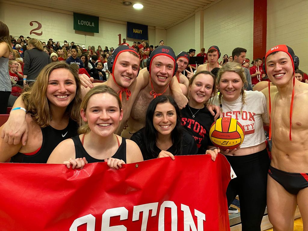 Photo of Gaby Grund (CGS’18, Sargent’20) with other members of the Water Polo team holding a Boston University banner.