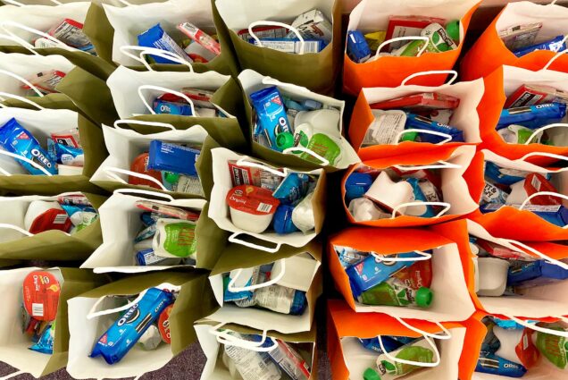 Aerial view of orange and white gift bags passed out as care packages to students still in residence on BU's campus. The bags contain an array of treats including oreos, candy, granola bars, popcorn, and juice, along with a “good luck on your finals” message from Residence Life.