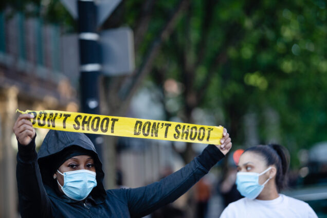 A protestor in Boston on May 31 holds up yellow tape that reads "Don't Shoot"