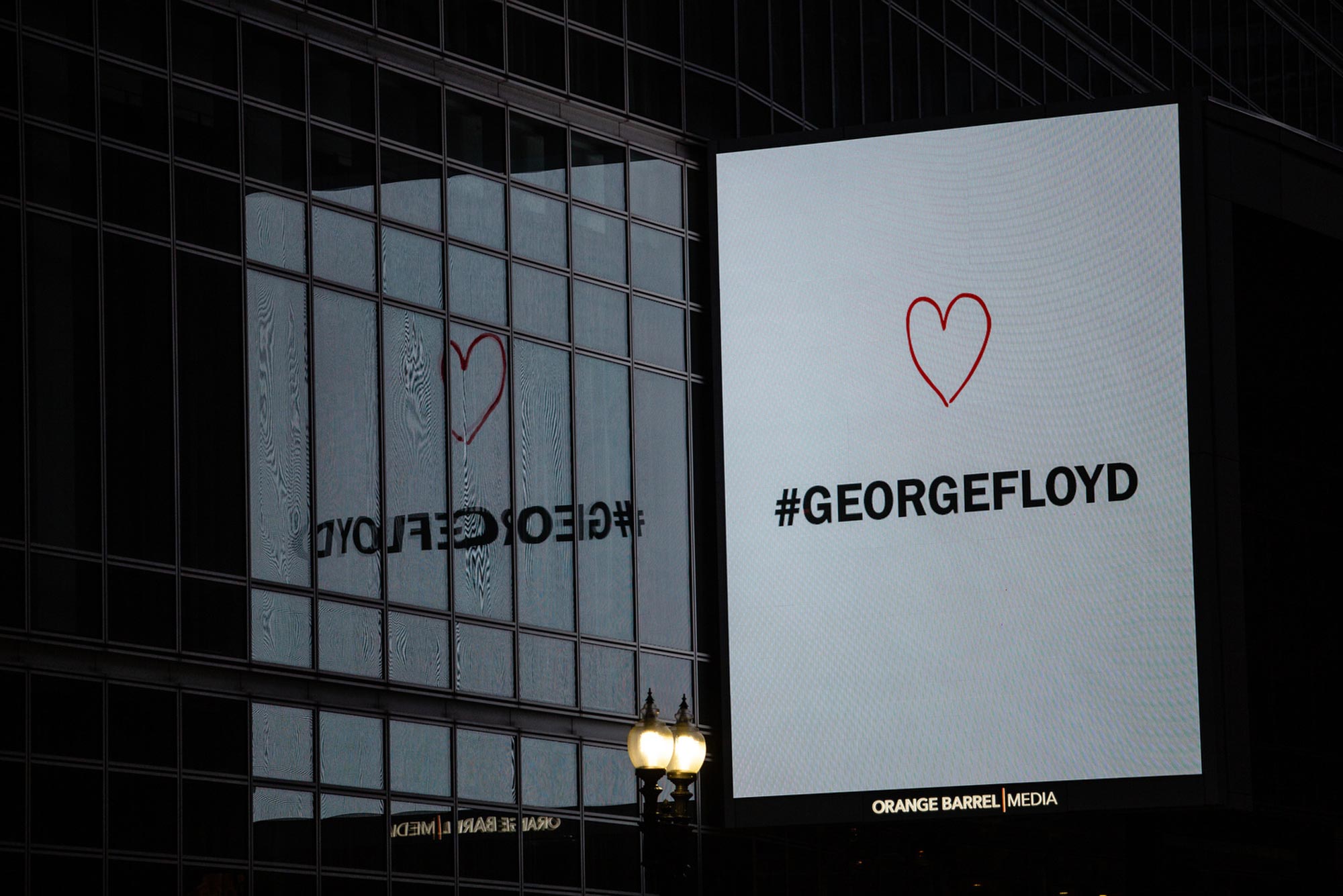 A digital sign overlooking protests in downtown Boston that reads "George Floyd" with a heart above the text