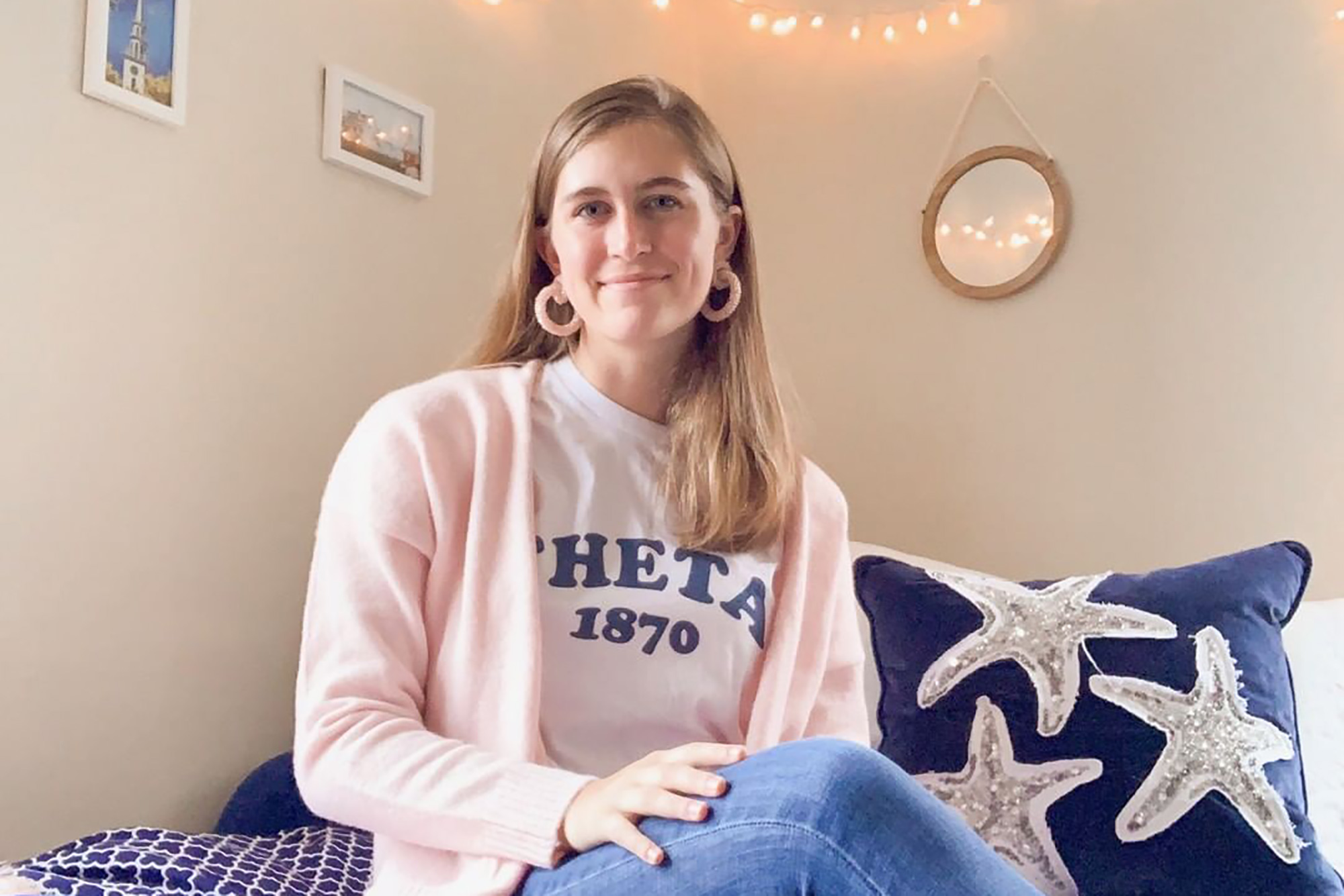 Photo of Caroline Olesky (CGS‘20, CAS‘22) in a door room. She wears a "THETA 1870" shirt.