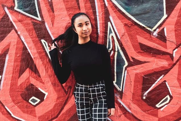 Portrait of Josee Matela (COM’20, Pardee’20) against a graffiti covered wall.