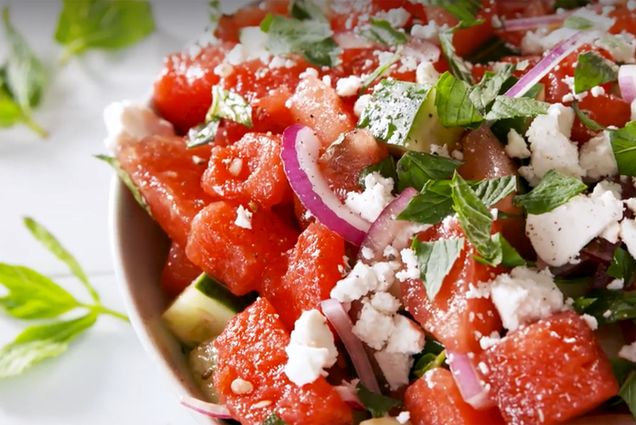 Closeup shot of a bowl of watermelon and cucumber salad with feta and mint.