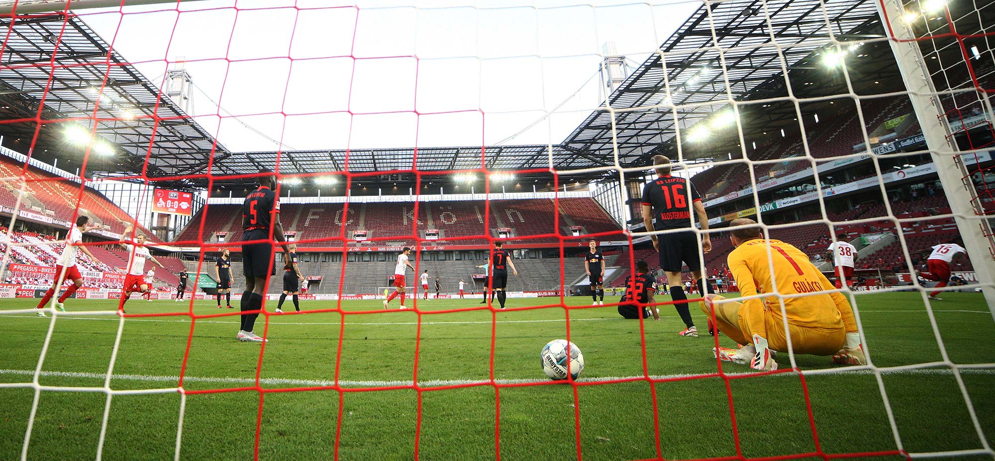 Photo of a Bundesliga match, FC Cologne v RB Leipzig. Pictured is RB goalkeeper, Peter Gulacsi, remote, and FC's Jhon Cordoba, Cordoba, sports: football. The photo is taken from behind the net, an empty stadium is seen in the background. Match was played on June 1, 2020.