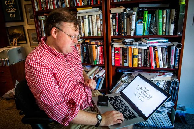 A photo of Andrew David working from his Watertown home on his laptop teaching his class on the history of the American presidency.