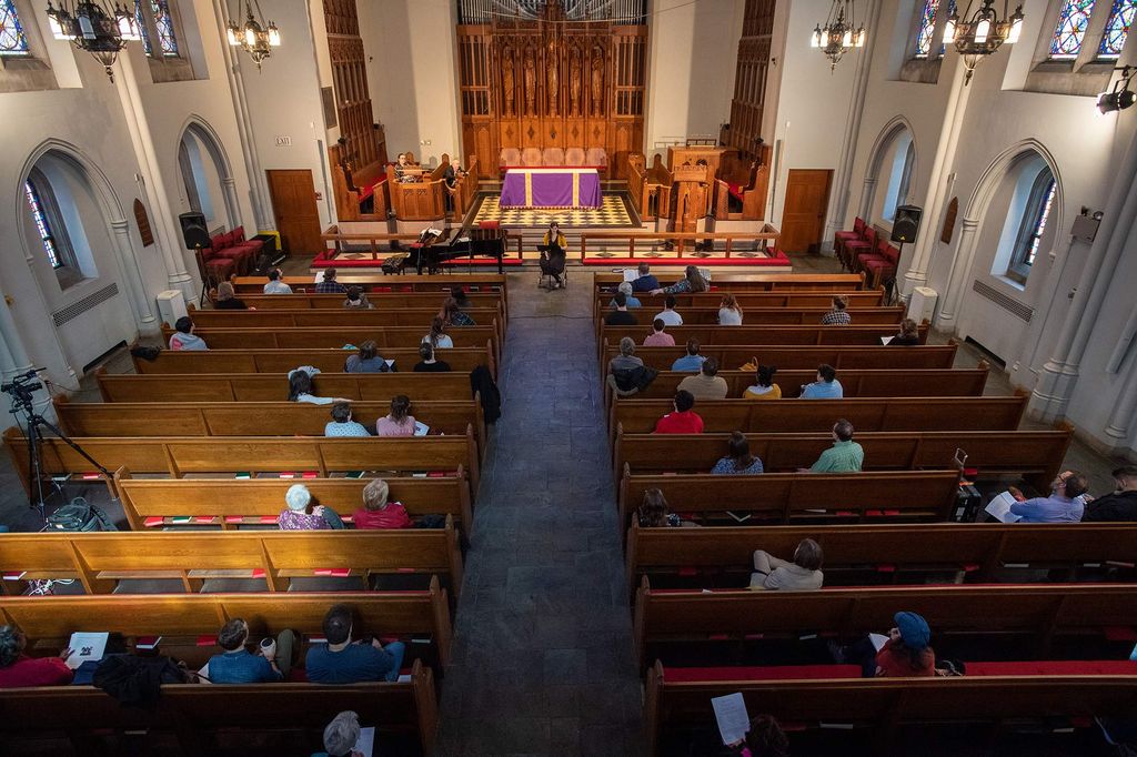 Bird's eye view of Marsh Chapel as Elizabeth Foster speaks. A few onlookers sit in the pews.