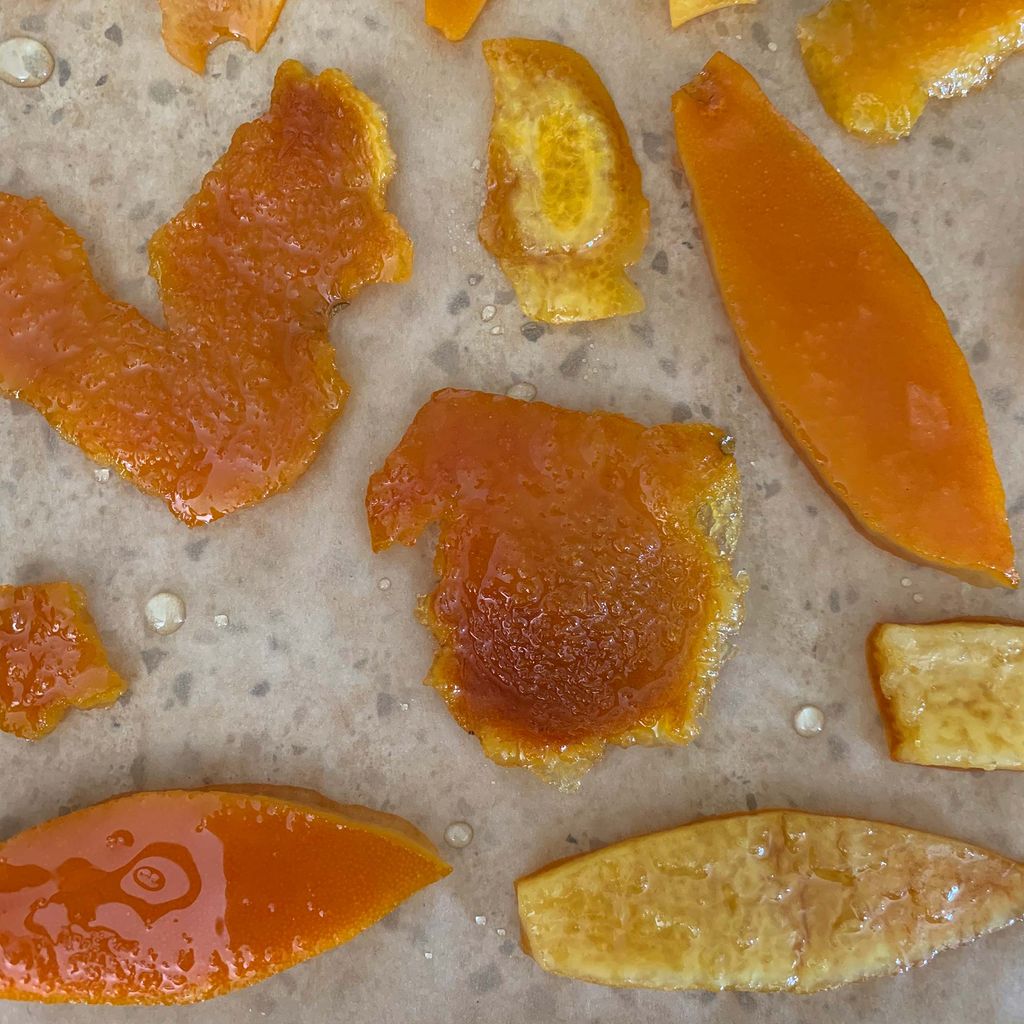 A set of orange peels simmered in simple syrup set out to dry, spaced out so they don't stick.