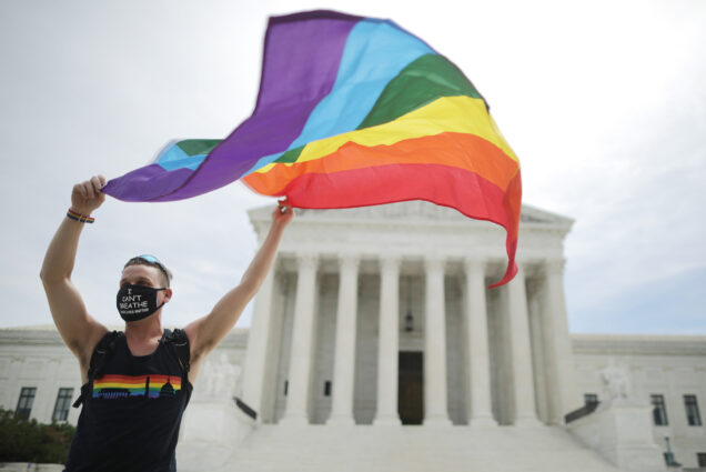 A person waving a rainbow Pride flag outside the Supreme Court building