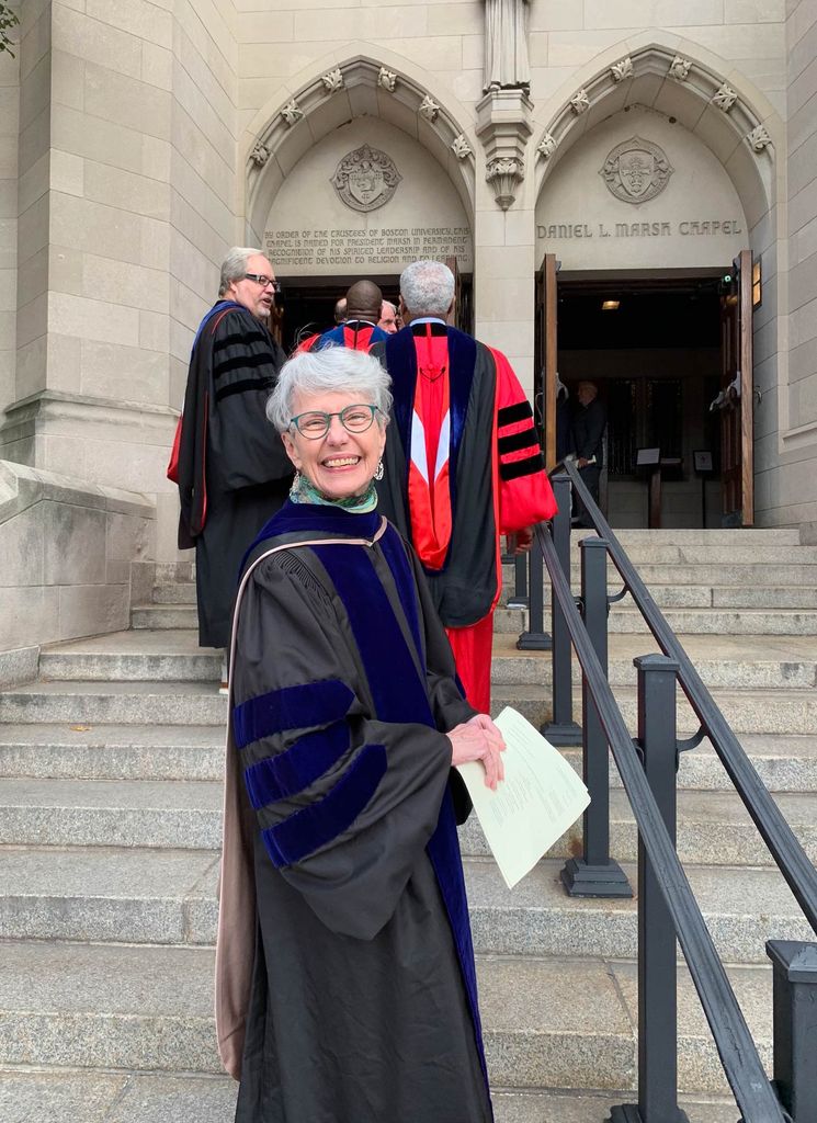 After more than 11 years as dean of STH, Mary Elizabeth Moore will retire on June 30. Here Moore smiles in a matriculation robe on her way into Marsh Chapel. A group of people in robes walk into the chapel behind her.