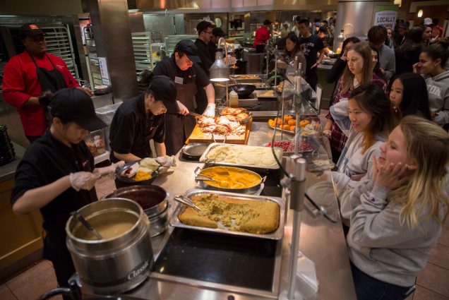 Dining hall workers dressed in black with hats carve and serve Thanksgiving dinner to eager students. Across the glass, Felicia Gordon (CAS '20) squeals with excitement as she waits for her first and seconds of Thanksgiving dinner in the West Dining Hall Thursday Nov. 16, 2017.