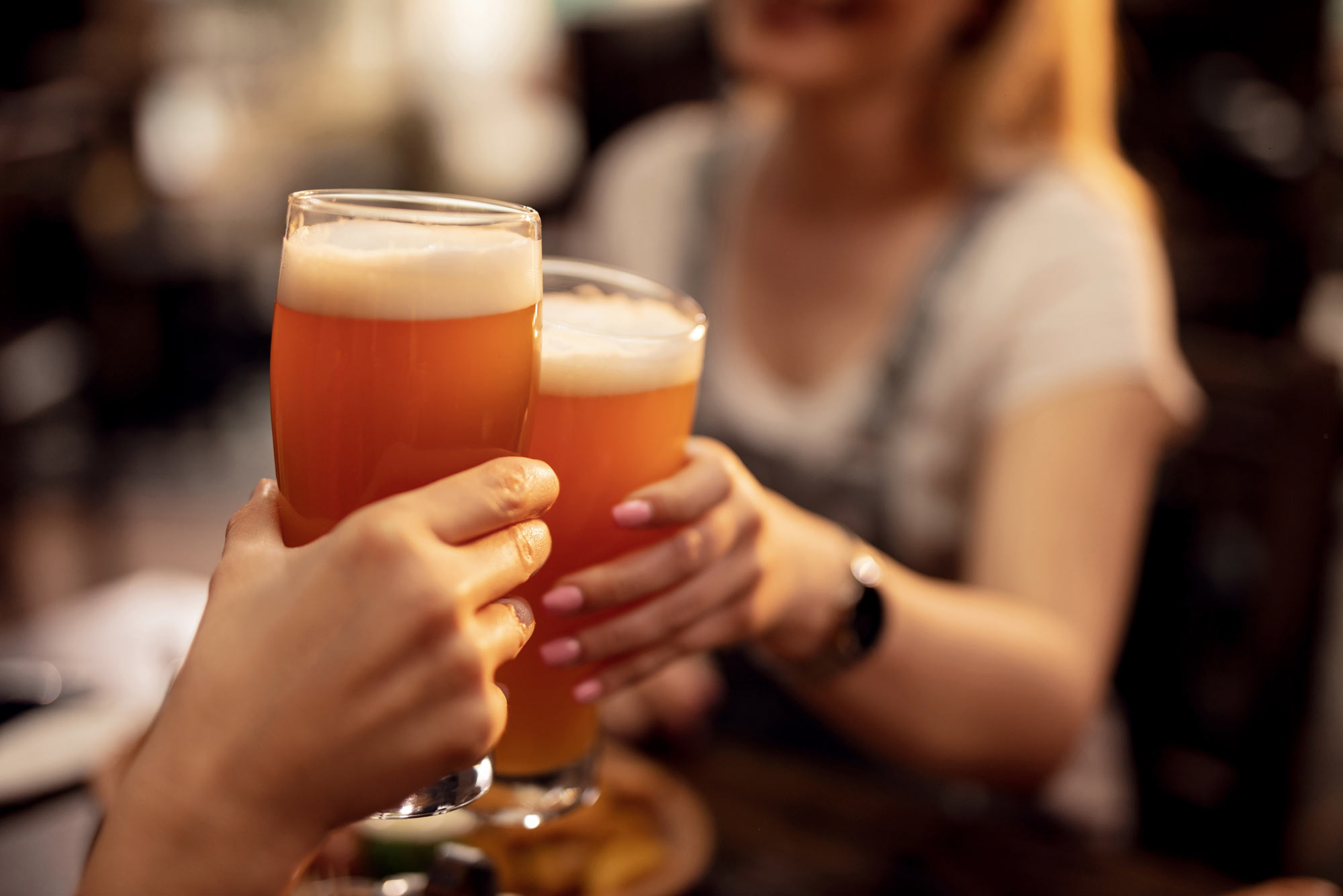 A photo of two people clinking beer glasses together