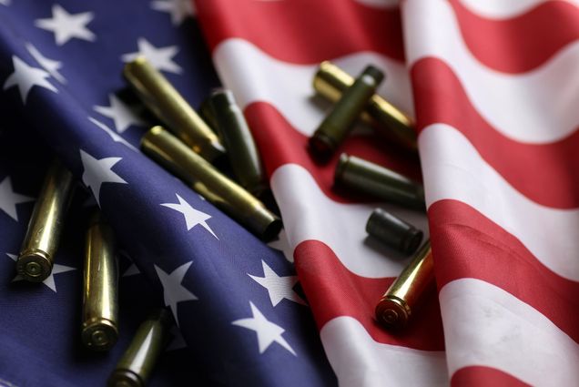 A photo of an American flag with bullet shell casings scattered on top of it