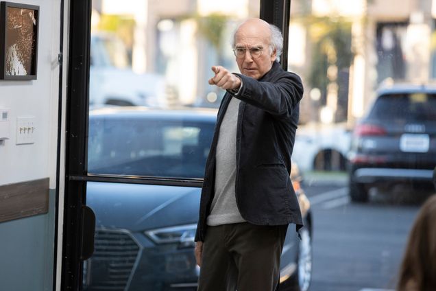 Shot from Larry David's sitcom Curb Your Enthusiasm. David stands on the sidewalk and points off into the distance.