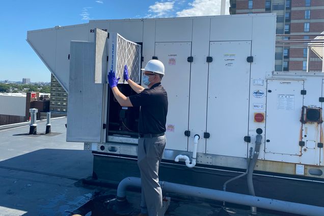 Elijah Ercolino, director of the Facilties Engineering Group, inspects an HVAC air filter on the roof of 1047 Commonwealth Ave.