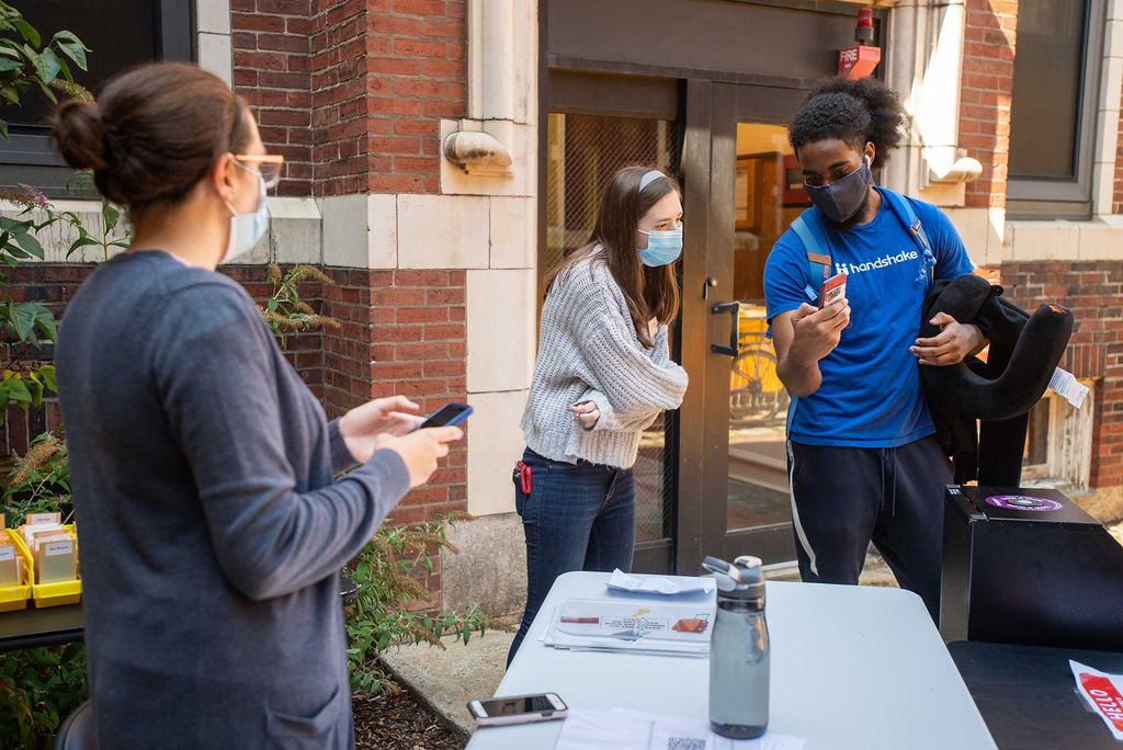 A student shows an RA proof of his scheduled COVID-19 test on his phone while getting his dorm key during Boston University Charles River Campus Fall semester 2020 move-in