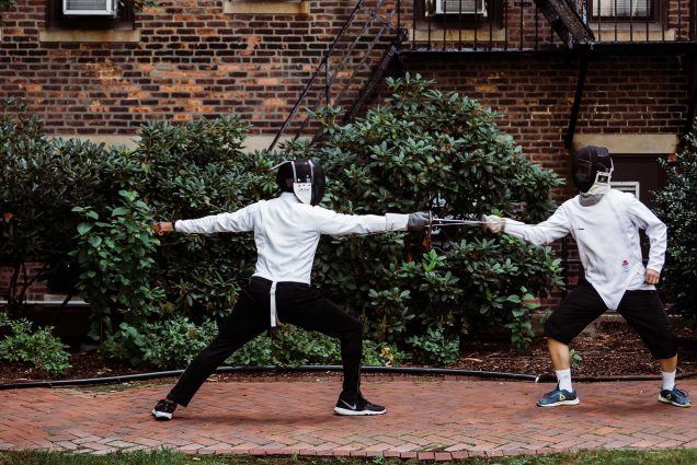 Members of the BU Fencing Club Alex Spencer (Pardee’21) and Yeung Sing Yo (CAS’22) practice on the BU Beach. Both fencers where white fencing jackets and fencing masks, their foils locked.