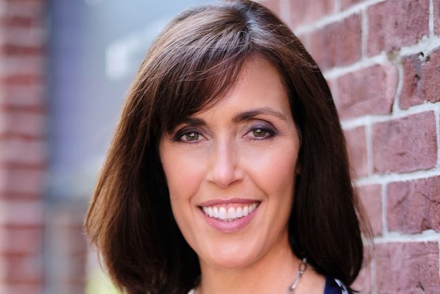 A portrait of Lorna Sabbia standing in front of a brick wall