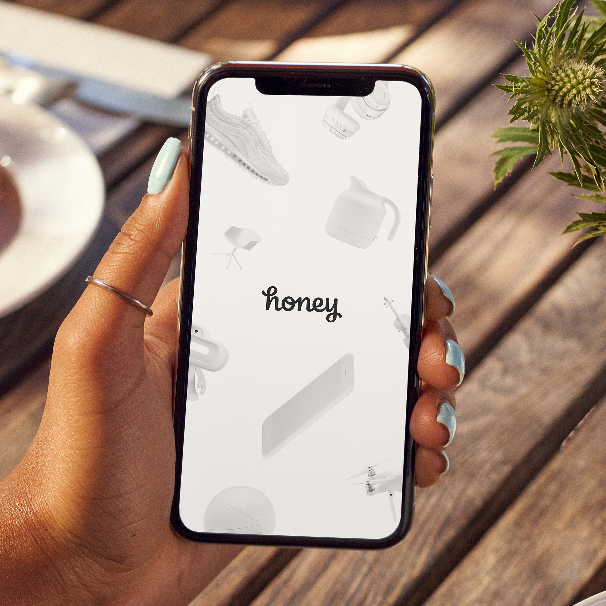 Hand holding a mobile phone displaying the Honey app homepage