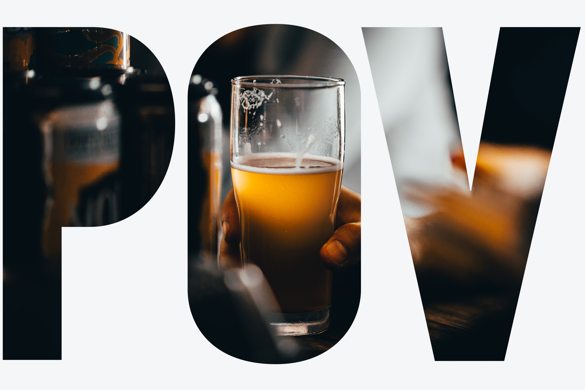 Photo of a hand holding beer; the beer and glass are in the light, while the background is blurry but resembles a bar. Overlay reads "POV"