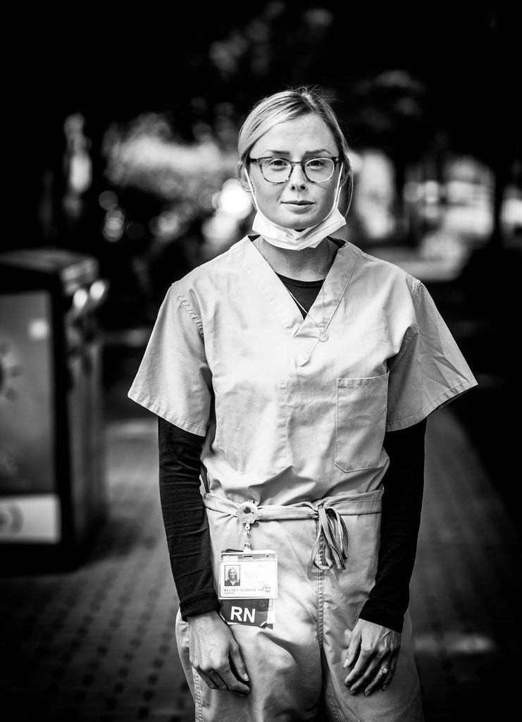 Black and white portrait of Kelsey Gilbride, BMC registered nurse, with her face mask hanging below her chin.