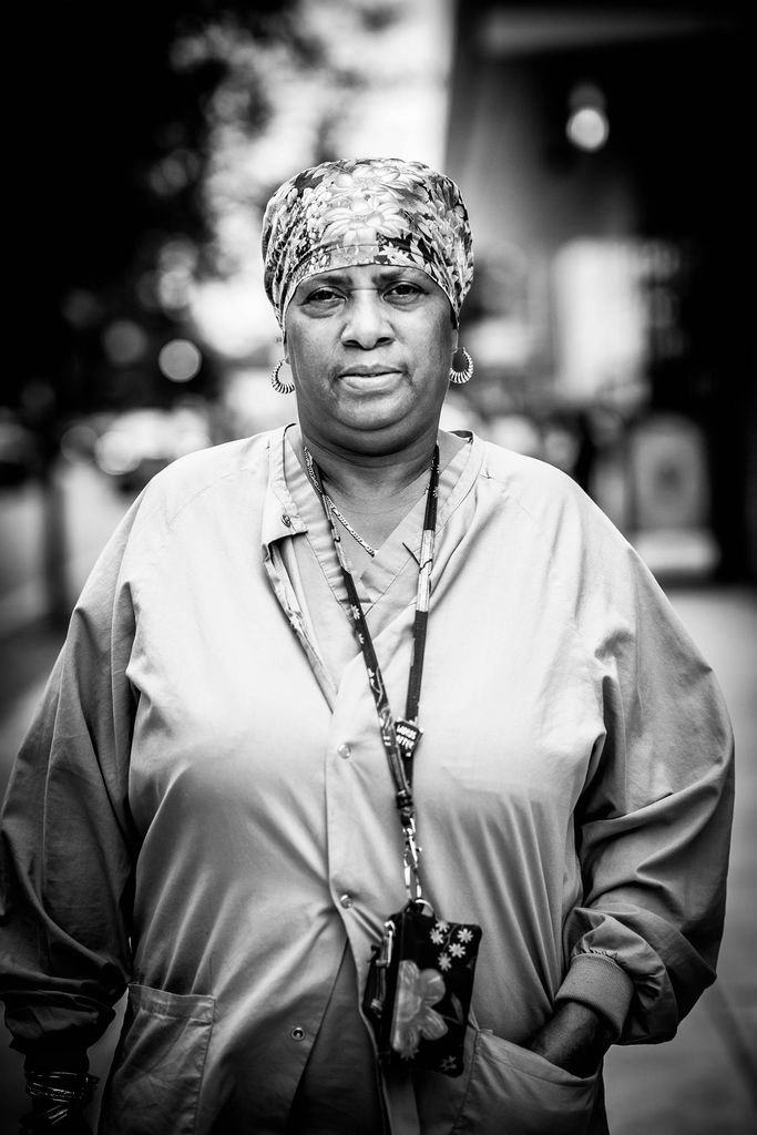 Black and white portrait of Keila Price, BMC administrative assistant who wears a lanyard and scrubs.