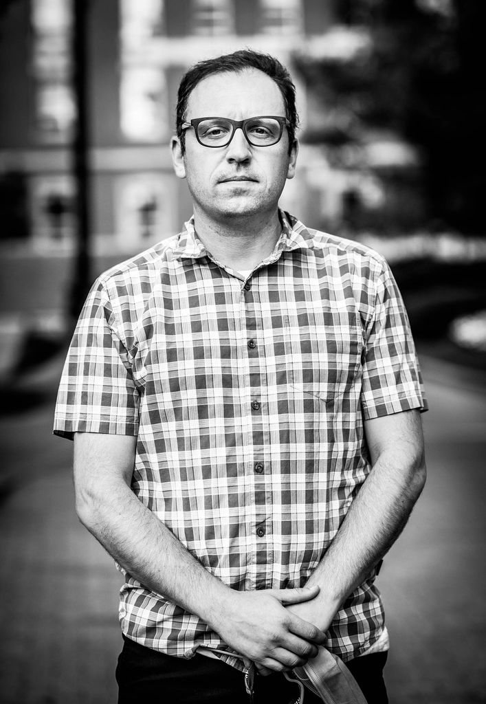 Black and white portrait of Joshua Barocas, BMC doctor of infectious diseases, and MED assistant professor of medicine wearing a checkered short-sleeve button-down shirt.