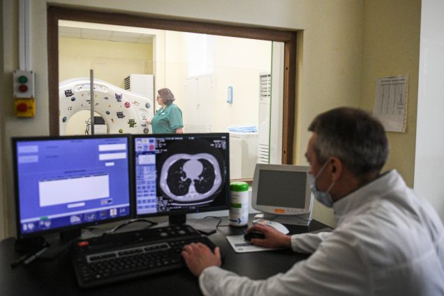 A photo of a doctor examining a CT scan of a patients lungs infected with COVID-19