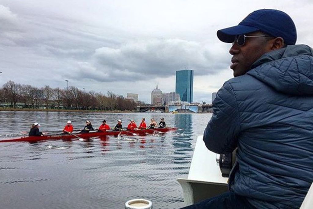 A photo of Malcolm Doldron watching as the women's rowing team practices on the Charles River