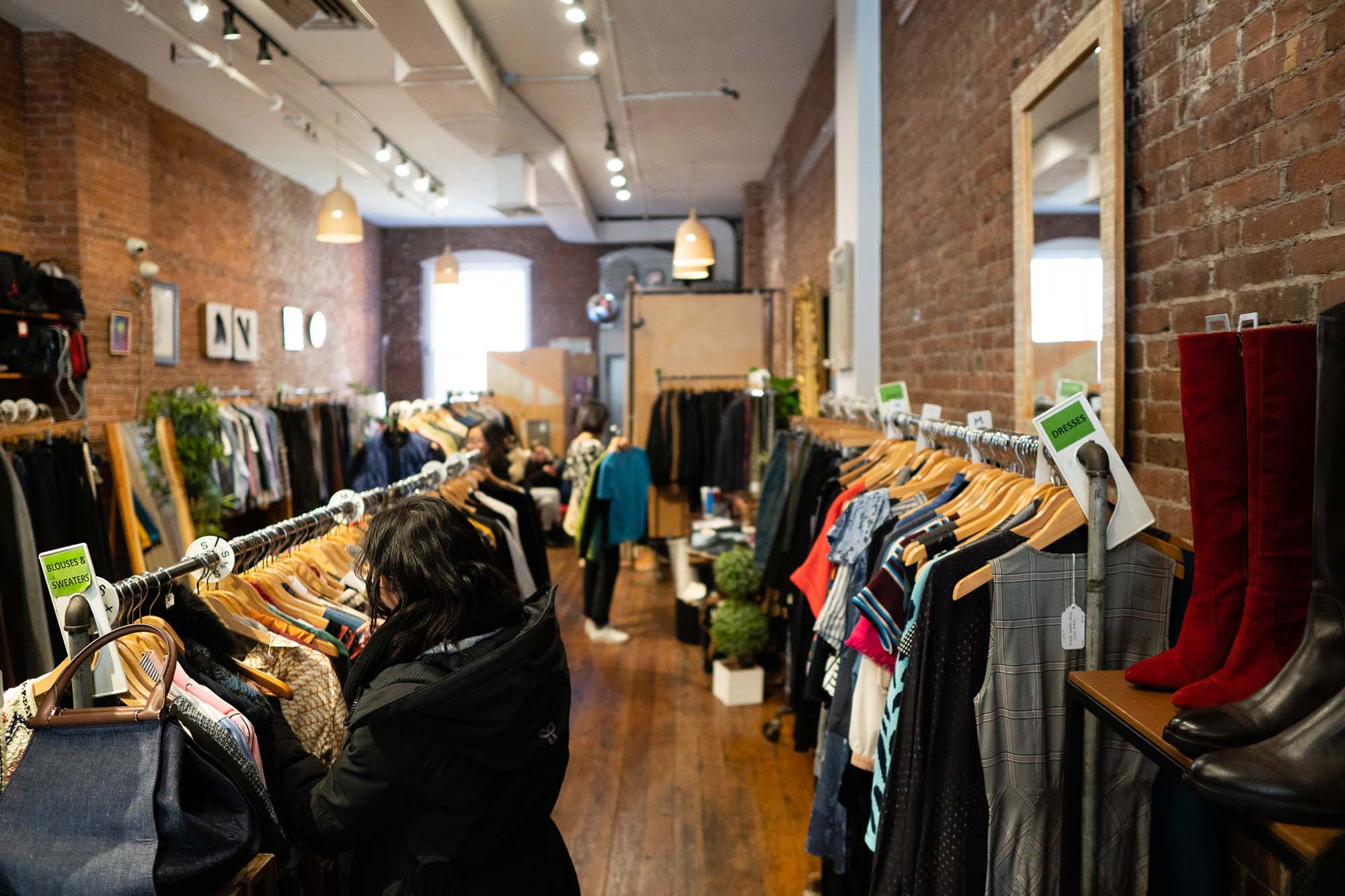 a photo of the interior of Boston's South End Boomerangs Special Edition. Customers browse through the clothing racks on a sunny winter day.