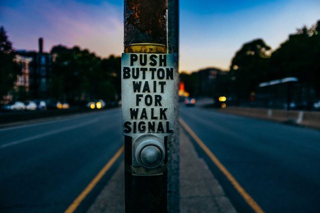 Detail photo of a Walk Signal Button at a crosswalk in Boston at dusk.