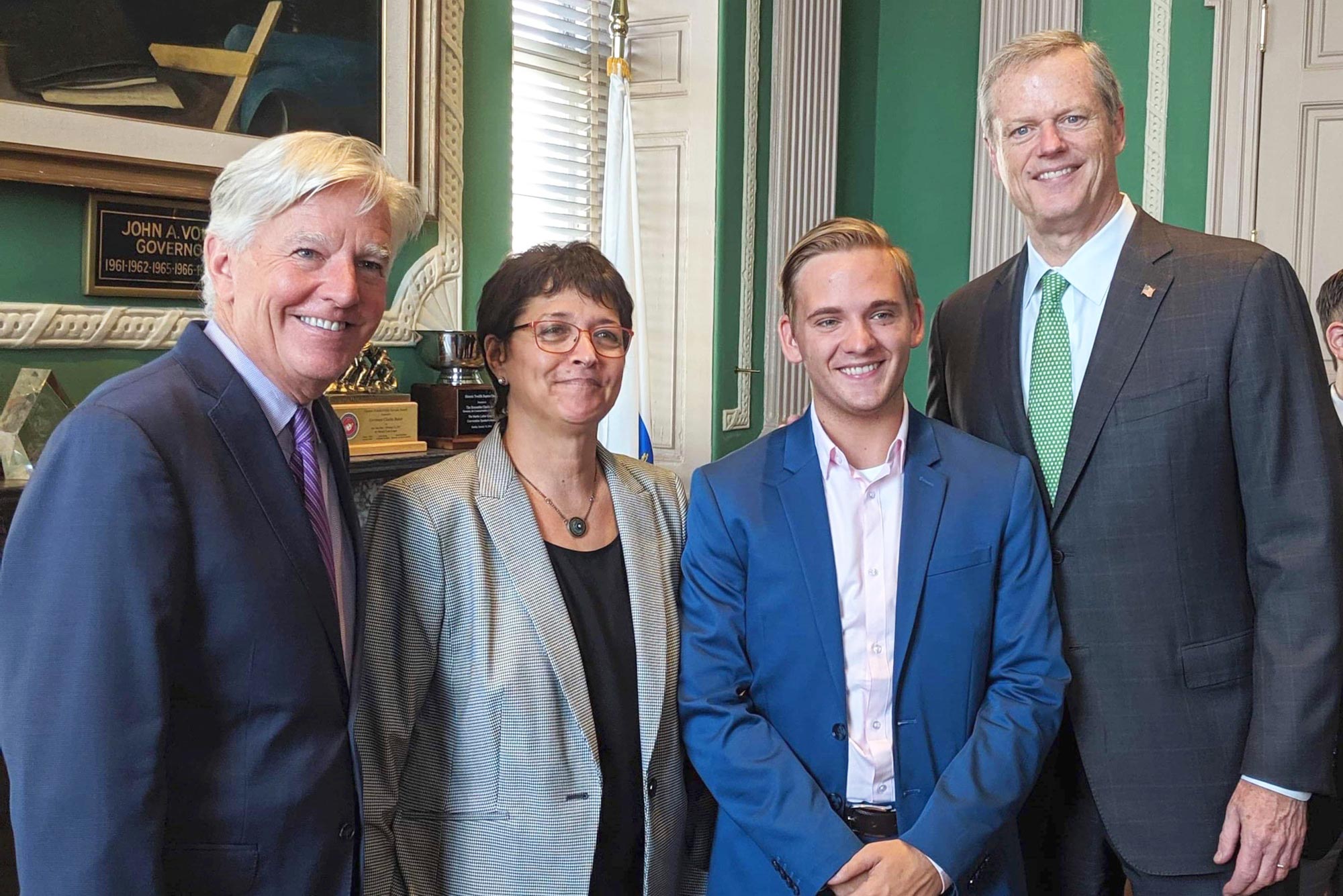 Photo of Jacob Binnall (LAW’23), in a blue suit with his hands folded, part of a Gen Z Republicans group, with Massachusetts Republican Governor Charlie Baker (far right) and two Democrats, state Representative Mindy Domb (R-3rd Hampshire) and Marty Meehan, a former US congressman and current president of the University of Massachusetts.