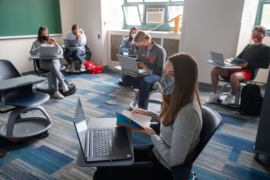 Photo of Sarah Wolf (ENG’24), foreground, in Emily Chua’s WR120 K8 Planet Ocean course, a first-year writing seminar focused on ocean science in CAS September 22. Students seen around Wolf sit at their desk on wheels, wears a mask and looks at their laptops.