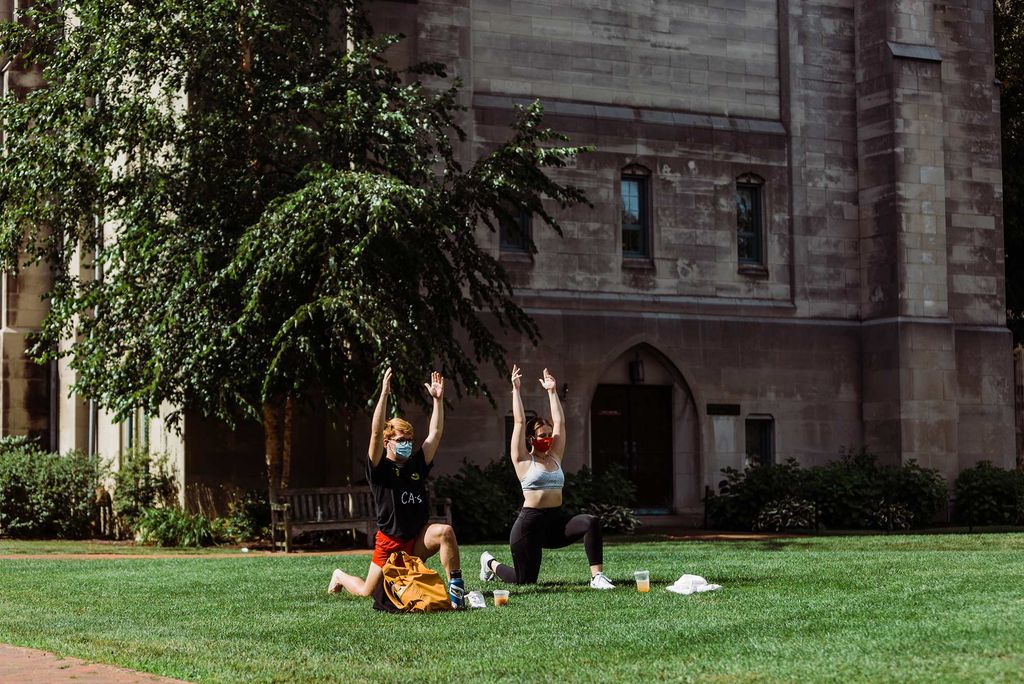 Photo of Trevor Turnbow (CFA’24) and Katelyn Thompson (CFA’24) practicing yoga on the BU Beach.