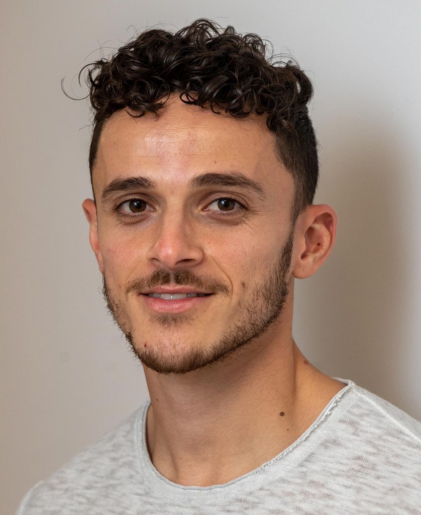 Headshot of Grad student and Center for Stuttering Therapy client Mason Blake (Wheelock’23). He smiles and wears a gray shirt.