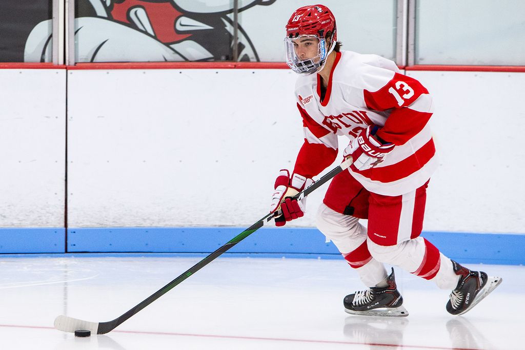 Photo of Drew Peterson (number 13) skating on the ice in possession of the puck.