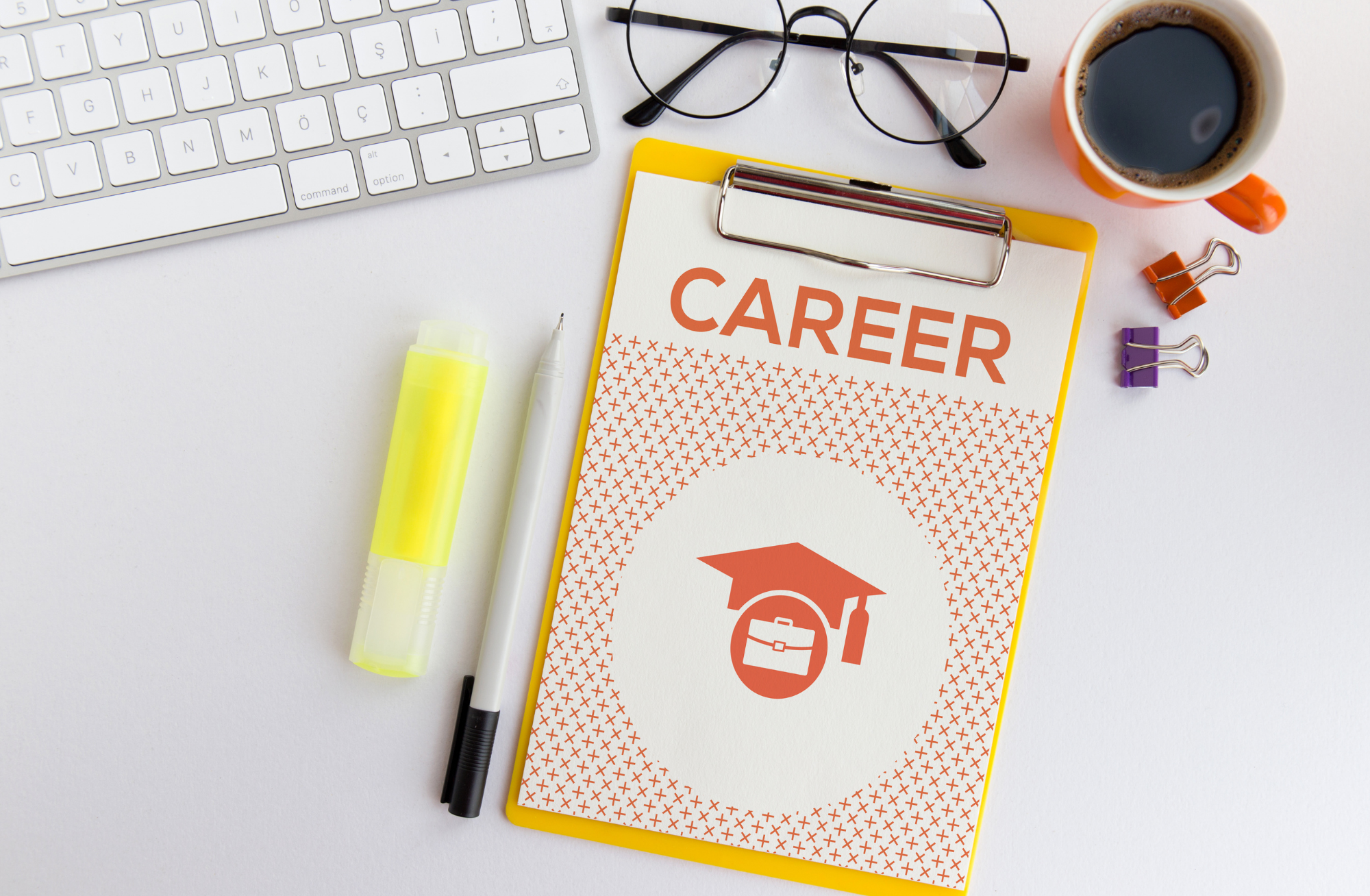 Photo of a clipboard with a piece of paper that says "Career" on it and a graphic with a graduation cap and briefcase. A pair of glasses, highlighter, pen and keyboard also rest on table.