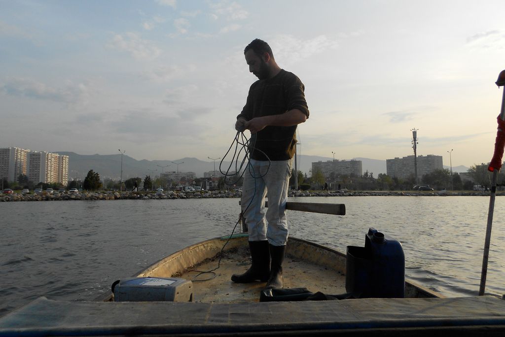 A photo of a fisherman standing on a boat with a line in his hands