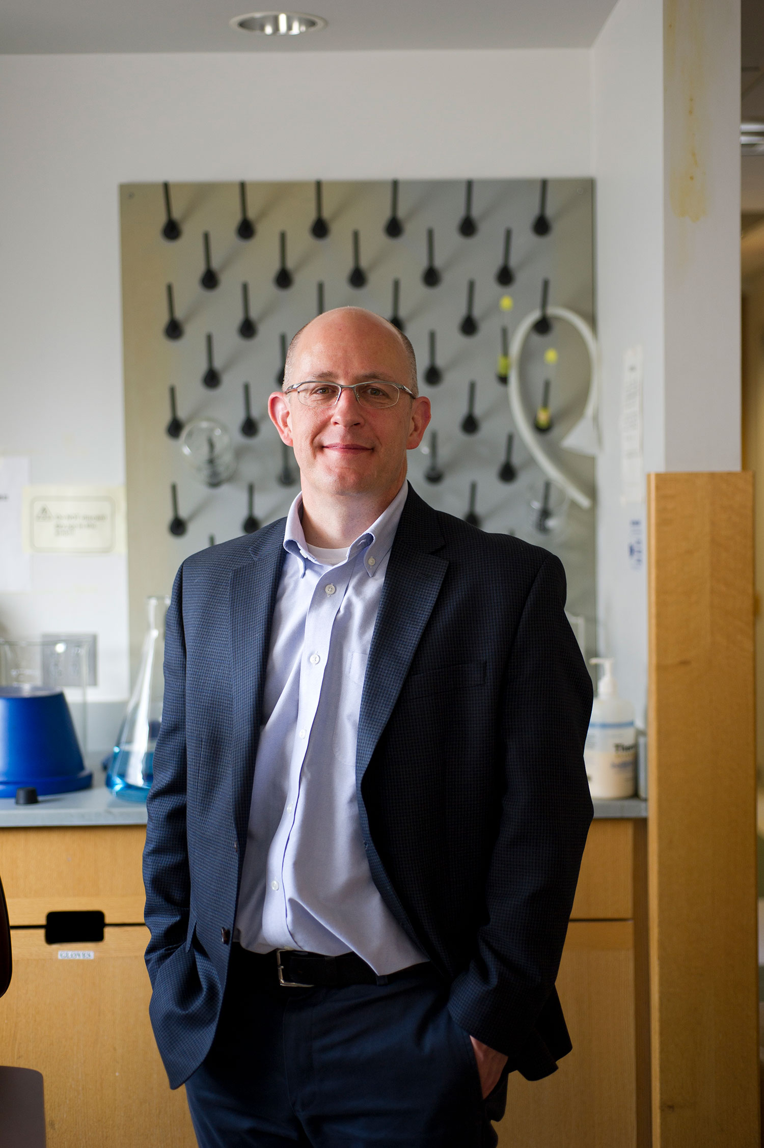 Portrait of Joseph Mizgerd, a pulmonary researcher and principal investigator, in his lab in the Medical Campus Housman Building. He wears a blue blazer and smiles.