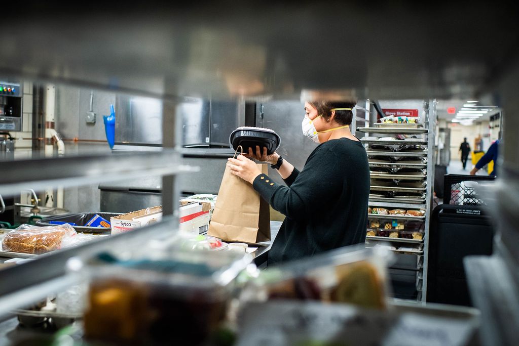 Photo of Catering manager Christine Cappadora filling brown bags with food for students in quarantine at Bay State Underground on October 19.