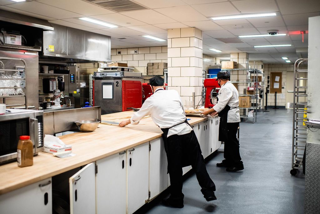 Photo de deux employés de cuisine en blouses et tabliers de chef travaillant dans les cuisines nouvellement rénovées du Food Hall.